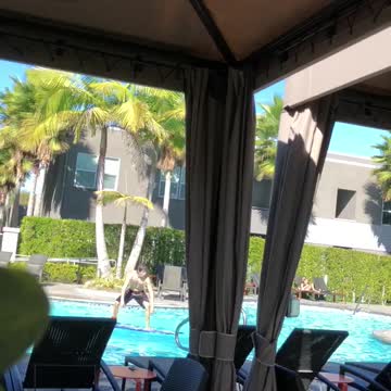Shirtless guy stands on surfboard in pool