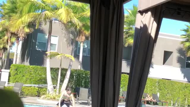Shirtless guy stands on surfboard in pool