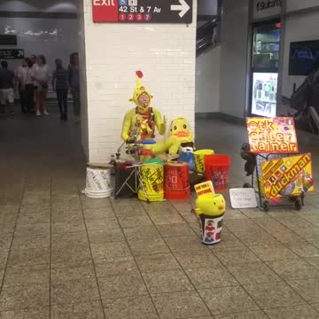 Man in yellow outfit plays drums in subway station