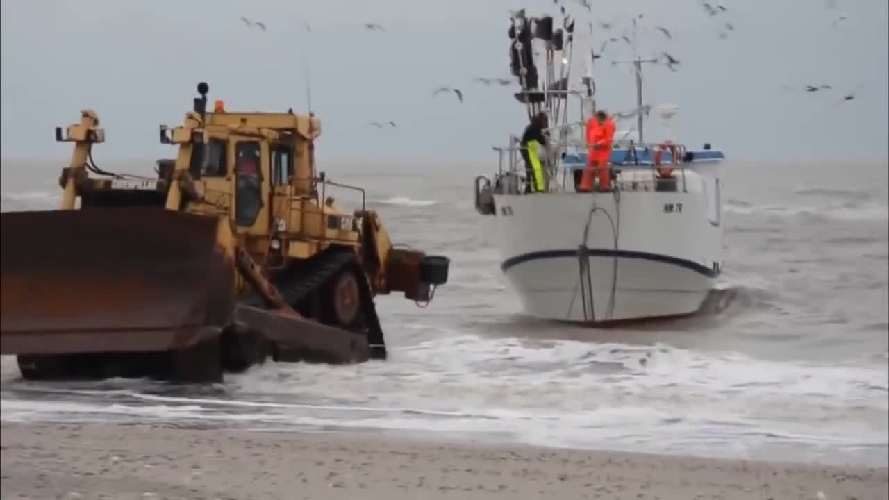 The bulldozer pulls the ship ashore