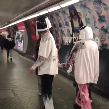 Couple wearing daft punk like helmets walks down subway station