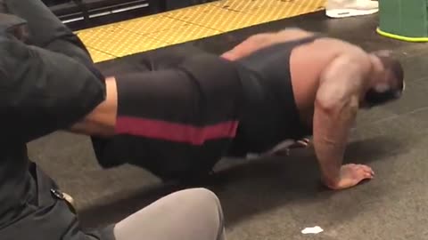 Man black red shorts push ups on subway floor