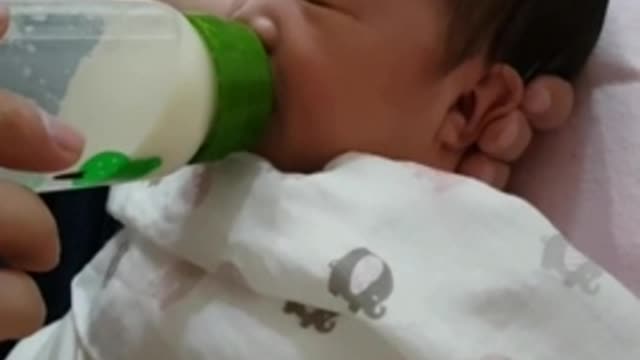 The newborn baby is eating powdered milk