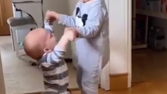 Brother helps the other to learn to walk, very beautiful