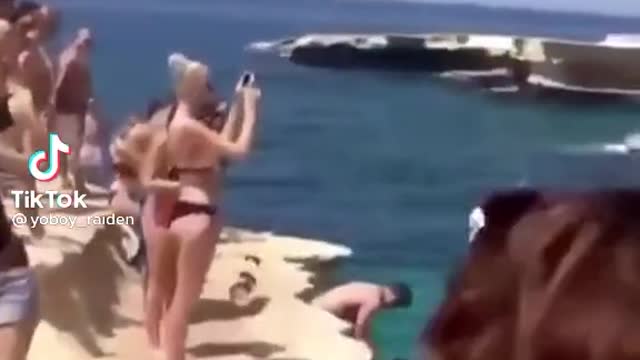 Funny crazy dog jumps from cliff in water