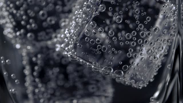 Poring liquid into a drinking glass with ice cubes