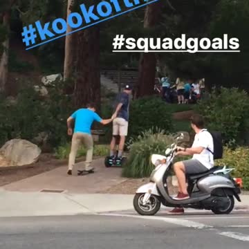 Guy on hoverboard helping guy on skateboard