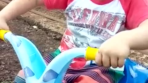 Little boy in a blue toy motorcycle falls over
