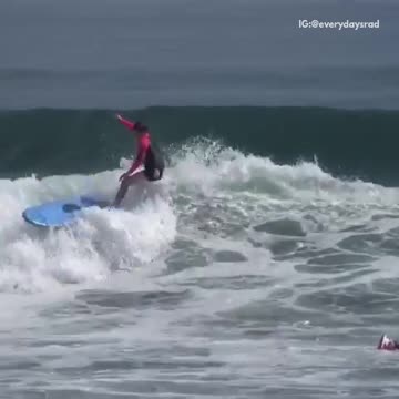 Guy in pink black wet suit surfboard slapping wave