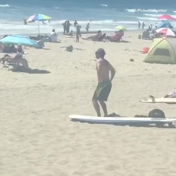 Man in green shorts on the beach does stretches