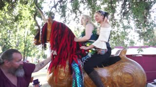 Two beautiful ladies, one of them a Mermaid, riding a Giant Rocking Unicorn