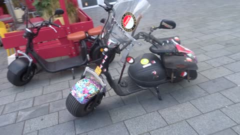 Twee elektrische scooters, de ene kaal, de andere zwaar versierd en volgehangen