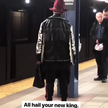 Guy in large red hat and black jacket turns around near subway