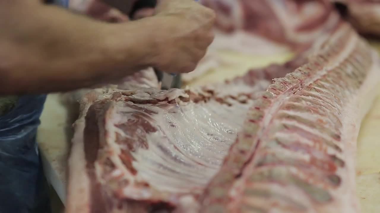 boning pork carcasses. butcher cuts pork carcasses in a meat factory