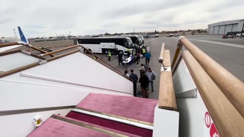 Illegals disembark from a white charter bus and board a complimentary white private jet.