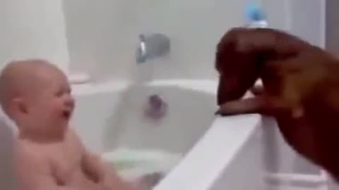 Baby in the bathtub plays with the little dog, very cute