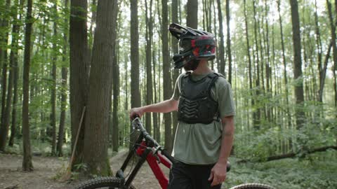 A Mountain Biker Standing in a Forest