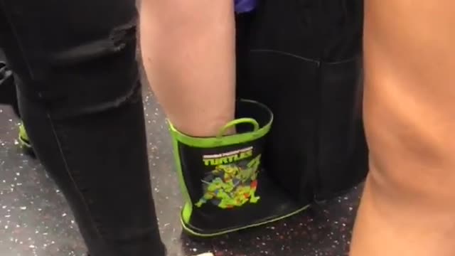 This a grown woman wearing ninja turtle rain boots