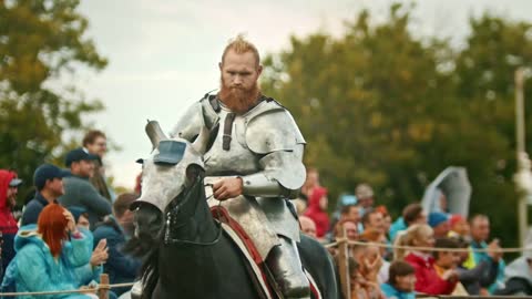 Knight riding a horse around the field - people watching him