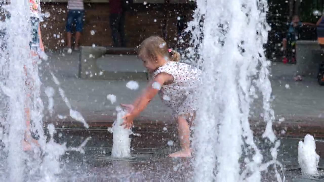 Nice Little Girl playing with water fountain