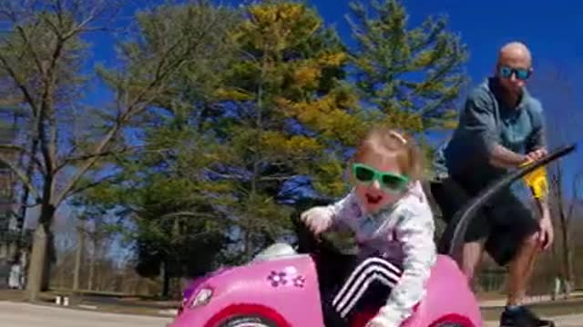 Man Riding on Skateboard Pushes Daughter Sitting in Toy Car