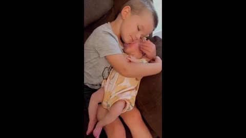 Big brother sweetly cuddles his new baby sister