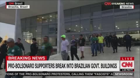 Bolsonaro supporters appear to be led out of a government building with zip-tie handcuffs