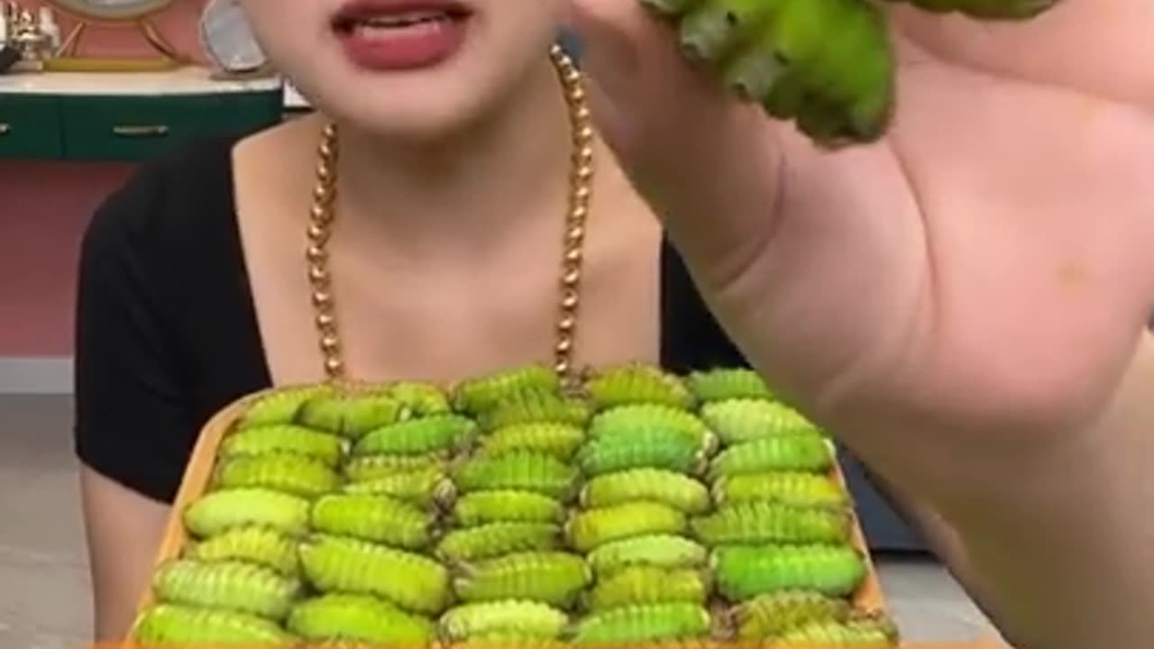 Beautiful Chinese girl eating green worms