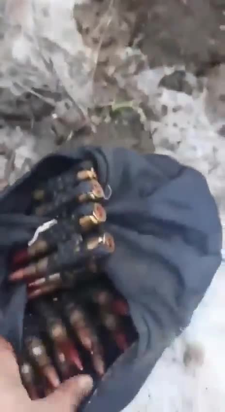 Local civilians unroll a machine gun from an abandoned Russian