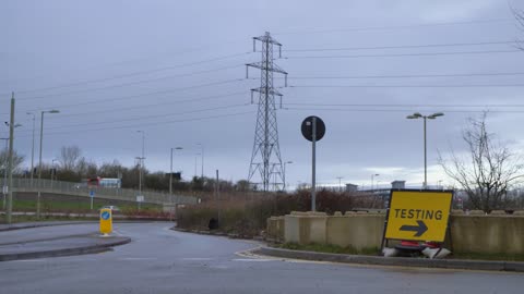 Wide Shot of Car and Lorry Passing COVID Testing Site Road Sign