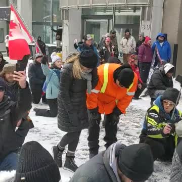 "Ottawa Protesters Kneel in Prayer" as lines of riot units face off with them