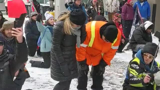 "Ottawa Protesters Kneel in Prayer" as lines of riot units face off with them