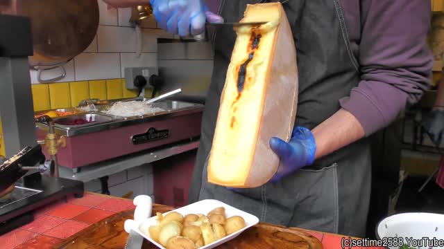 Yummy Swiss Raclette. Warm Melted Swiss Cheese with Egg and Potatoes. London Street Food