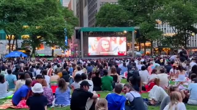 An open-air movie in a park in new york is crowded with people.