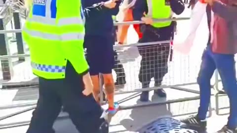 Protestor holding a St George's Cross is pushed over by a Met police officer.