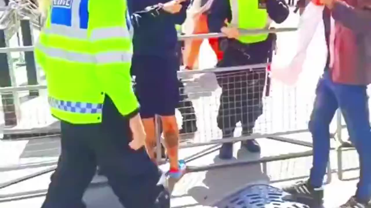 Protestor holding a St George's Cross is pushed over by a Met police officer.