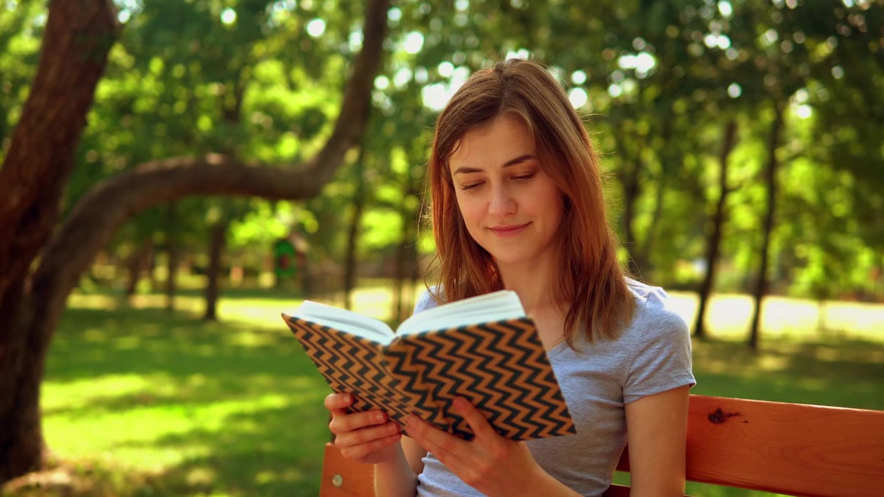Beautiful girl reading a book in the park