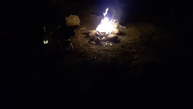 Campfire next to a river . Night time