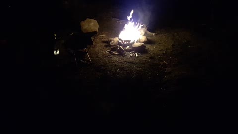 Campfire next to a river . Night time