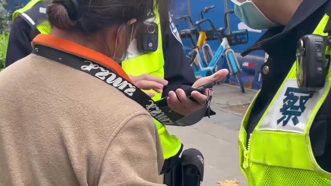 Chinese police officers make woman delete pictures and video of recent protests against the CCP