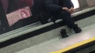 Man in black outfit clipping toe nails waiting for train