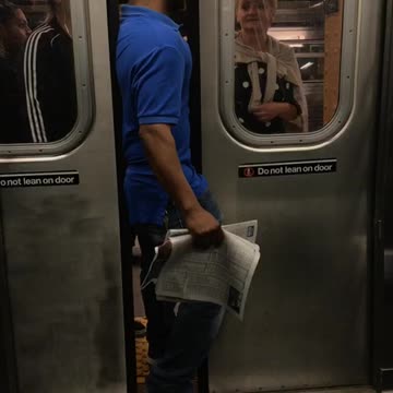 Man in a blue shirt standing between train doors