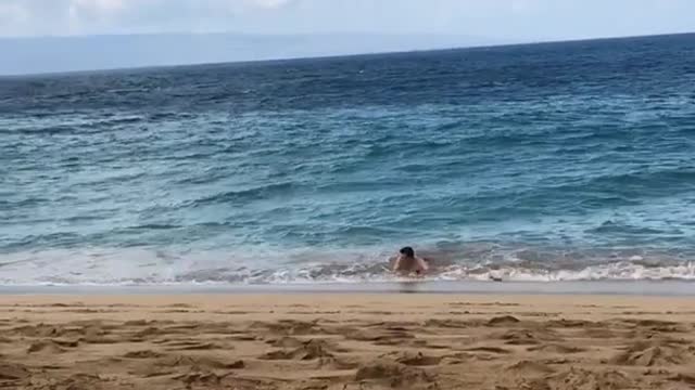 Guy in blue shorts on skimboard in water