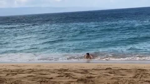 Guy in blue shorts on skimboard in water