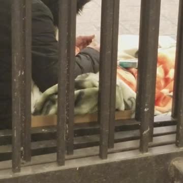 Parka person rolls cigarette on sidewalk