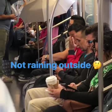 Person on subway standing near door with grey umbrella open