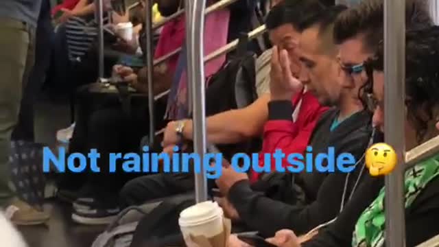 Person on subway standing near door with grey umbrella open