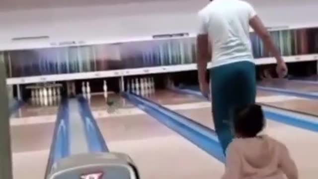 This baby tries to play Bowling but his dad runs toward him and fall together