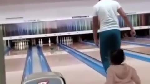 This baby tries to play Bowling but his dad runs toward him and fall together