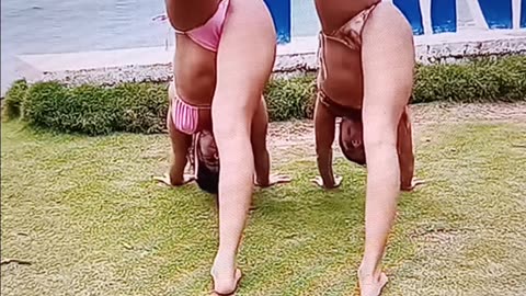2 friends doing yoga by the water